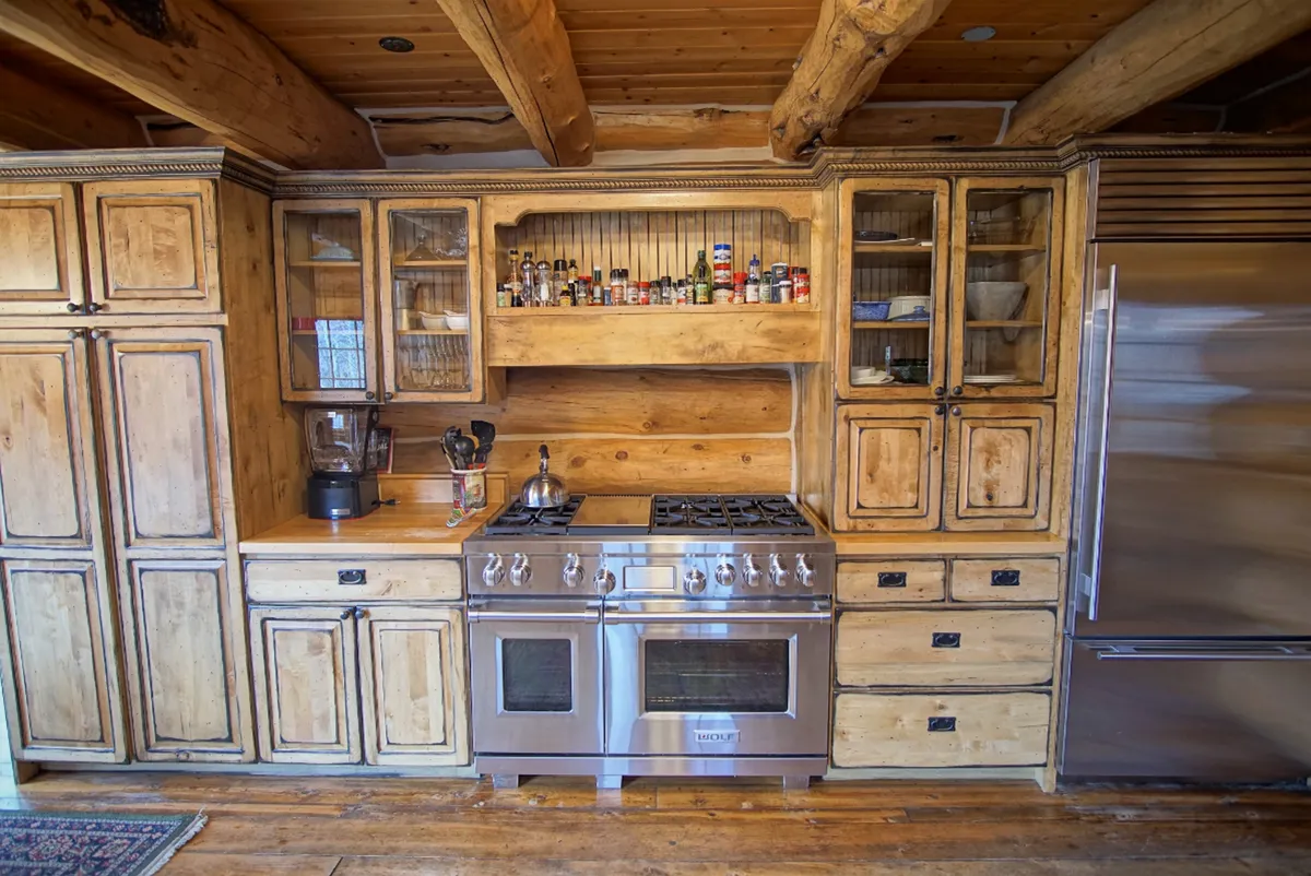 A spacious kitchen featuring a stainless steel stove, wooden cabinetry, and a well-stocked spice rack. The scene hints at warmth and activity, with ample space for multiple people to gather and cook together.